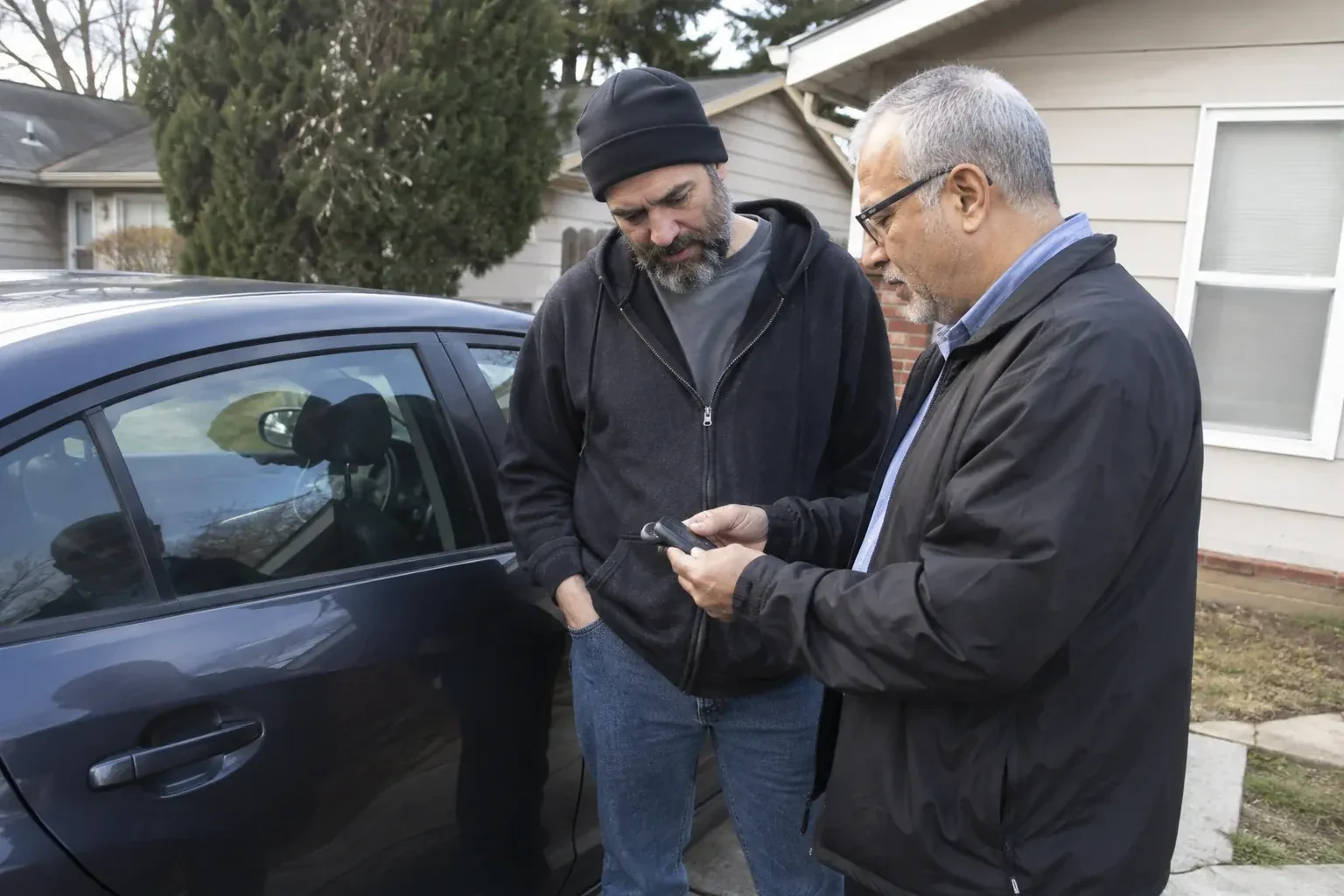 Two adults discussing a key fob beside a parked car. — Car Lockout Service, Mississauga
